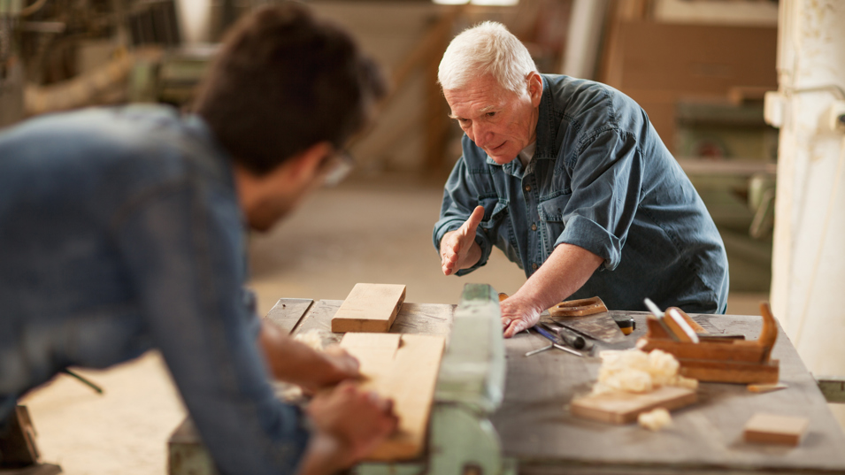 Ældre tømrer hjælper yngre tømrer